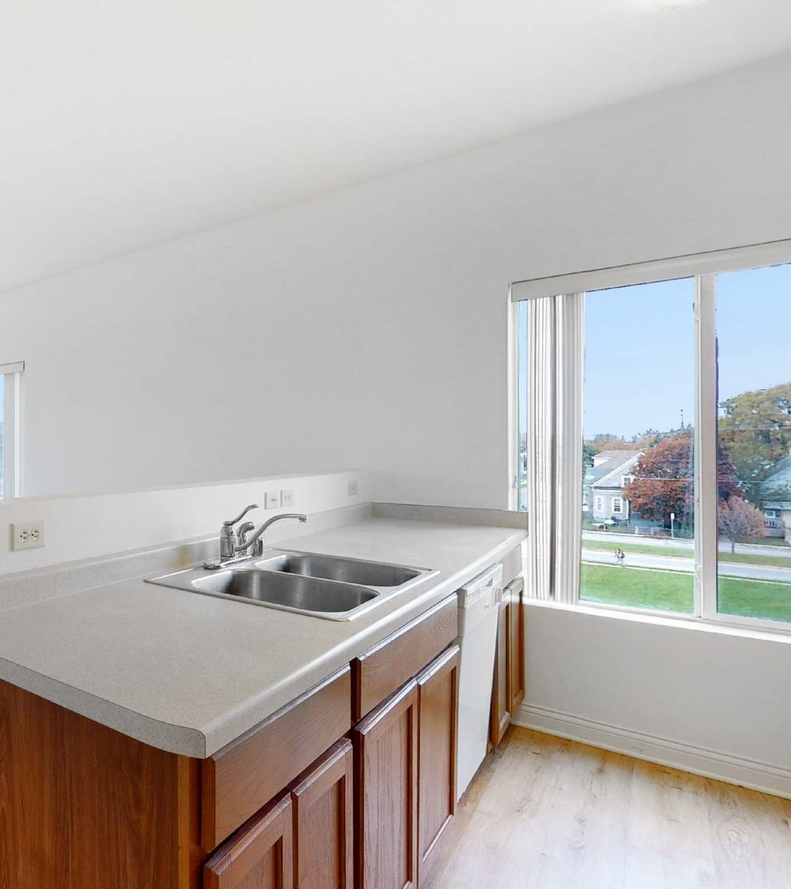 Uptown Brass Apartments open floor plan living room with plush carpeting, large windows and kitchen with breakfast bar